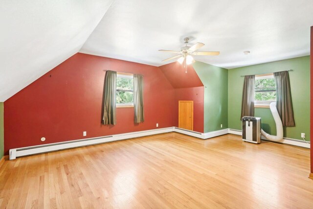 bonus room featuring wood-type flooring, vaulted ceiling, a baseboard heating unit, and plenty of natural light