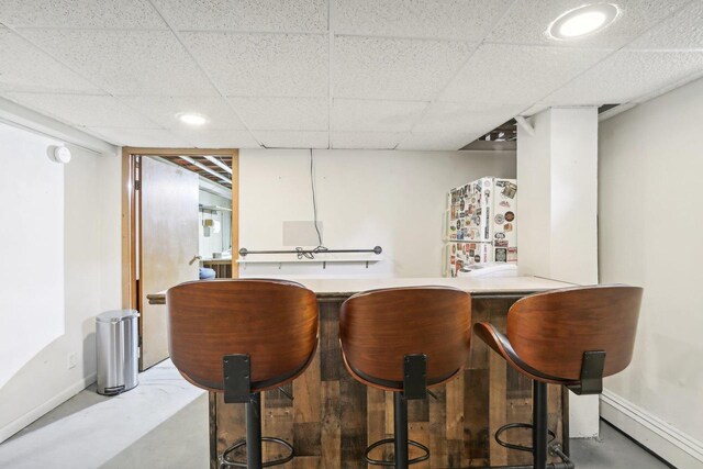 bar with concrete flooring and a paneled ceiling