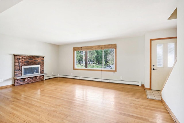 unfurnished living room with a baseboard radiator, a fireplace, and light hardwood / wood-style floors