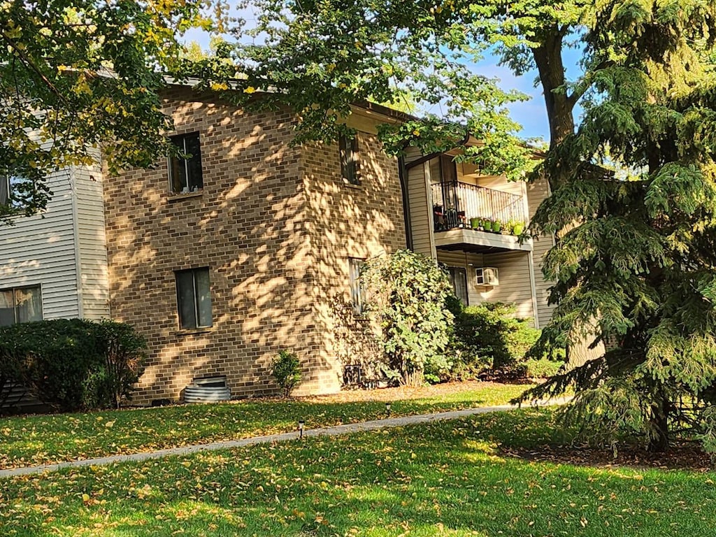 view of side of home with a balcony and a yard