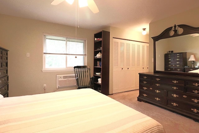 carpeted bedroom featuring ceiling fan, a wall mounted AC, and a closet