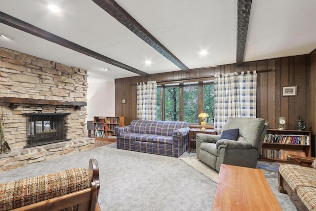 living room with light carpet, wood walls, a stone fireplace, and beam ceiling