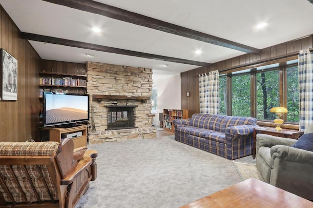 living room with beam ceiling, a stone fireplace, light carpet, and wooden walls