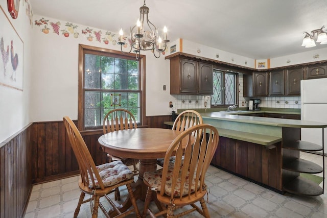 dining area featuring a notable chandelier, plenty of natural light, sink, and wood walls