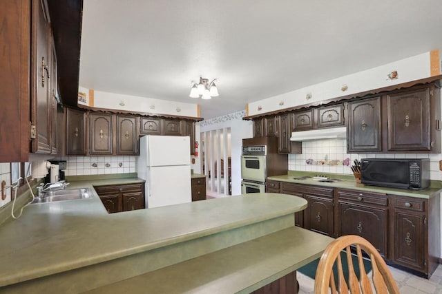 kitchen with kitchen peninsula, dark brown cabinetry, sink, white appliances, and tasteful backsplash