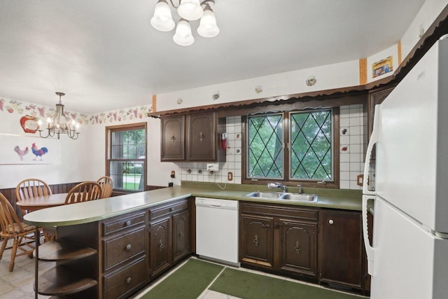 kitchen with a notable chandelier, white appliances, dark brown cabinetry, pendant lighting, and kitchen peninsula