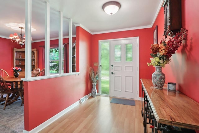 foyer featuring ornamental molding, light hardwood / wood-style floors, and an inviting chandelier