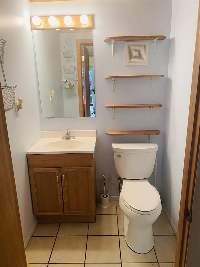 bathroom with toilet, vanity, and tile patterned floors