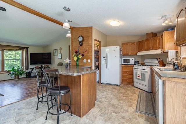 kitchen featuring sink, light hardwood / wood-style flooring, white appliances, vaulted ceiling, and kitchen peninsula