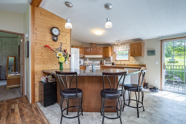 kitchen with a wealth of natural light, light hardwood / wood-style flooring, decorative light fixtures, and wood walls