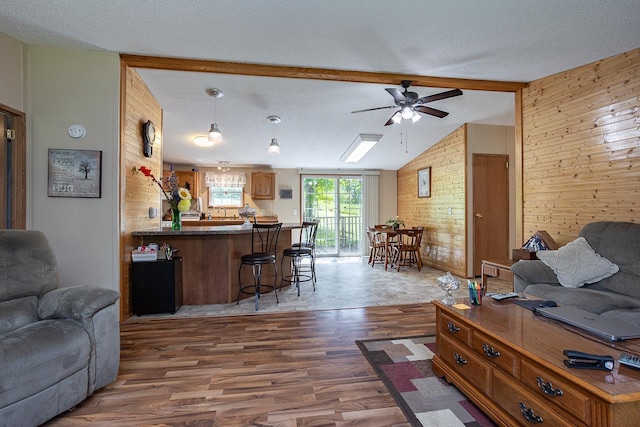 living room with ceiling fan, wooden walls, hardwood / wood-style floors, and a textured ceiling