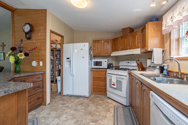 kitchen featuring wood walls, sink, white appliances, a textured ceiling, and light tile patterned floors