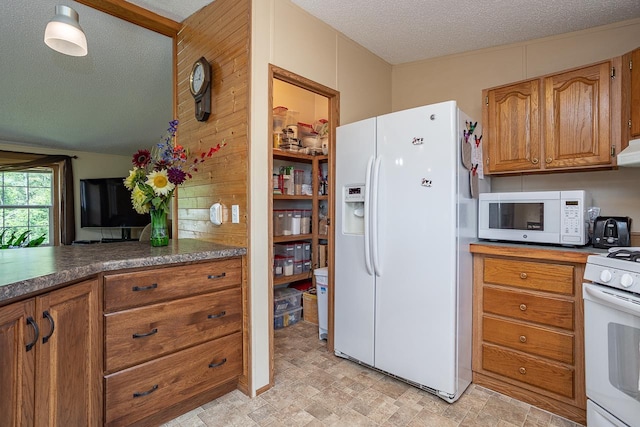 kitchen featuring a textured ceiling, white appliances, and light tile patterned floors