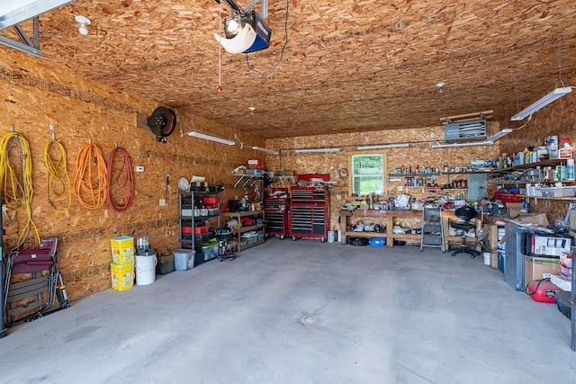 garage featuring a garage door opener, a workshop area, and electric panel