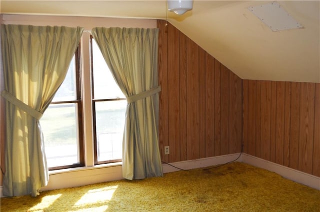 additional living space featuring light carpet, vaulted ceiling, and wood walls