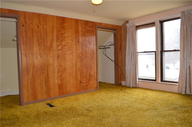 carpeted spare room with wooden walls