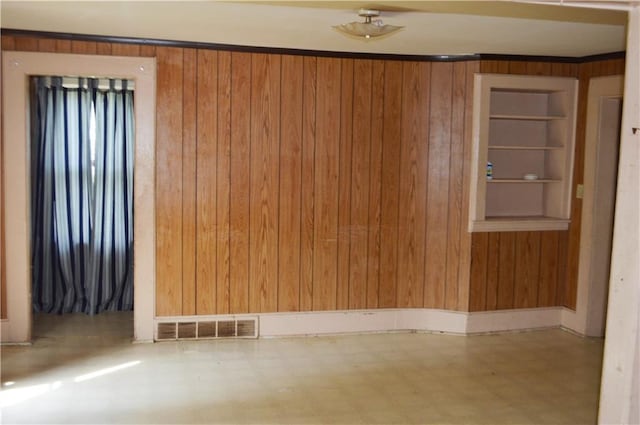 empty room with built in features and wood walls