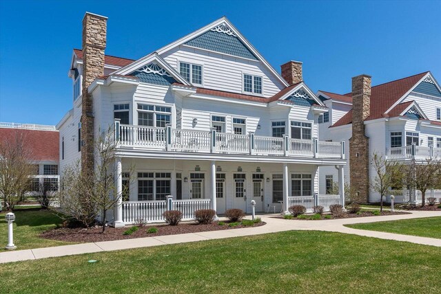 view of front of house with a balcony, a front yard, and covered porch