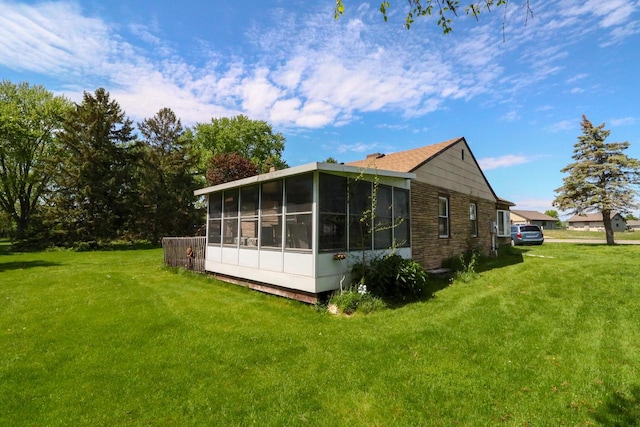 view of side of home with a sunroom and a lawn