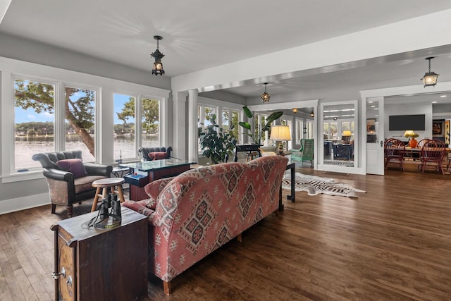 living room featuring a water view, ornate columns, and dark hardwood / wood-style floors