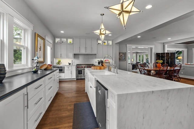 kitchen featuring stainless steel appliances, sink, pendant lighting, white cabinets, and dark hardwood / wood-style flooring