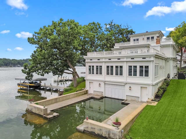 rear view of house with a balcony, a yard, and a water view