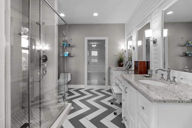 bathroom with tile patterned flooring, vanity, walk in shower, and toilet