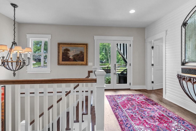 foyer featuring hardwood / wood-style flooring, a notable chandelier, and french doors