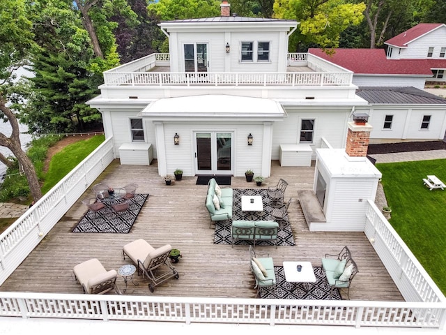 back of house featuring french doors, a deck, and an outdoor living space with a fireplace