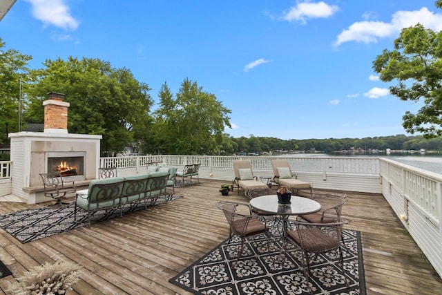 deck with a water view and an outdoor living space with a fireplace