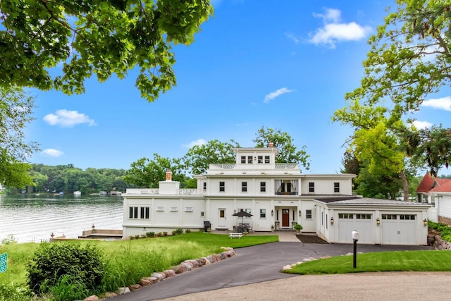 view of front of house featuring a front yard, a garage, and a water view