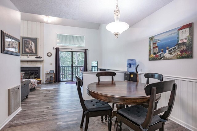 dining space featuring a fireplace, a textured ceiling, and wood-type flooring