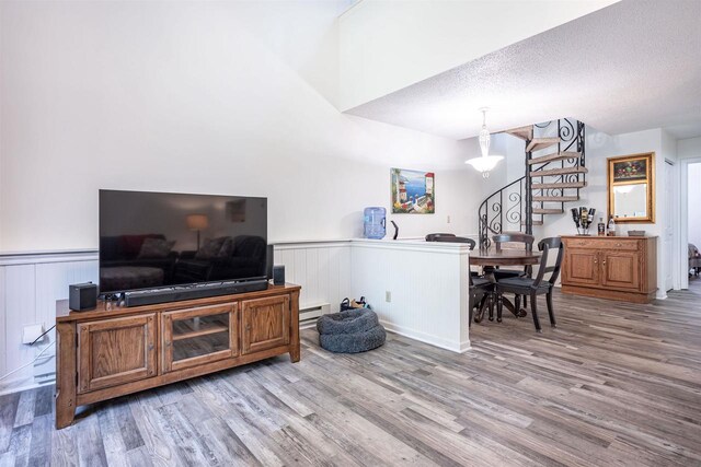 living room with a textured ceiling, an inviting chandelier, baseboard heating, and wood-type flooring