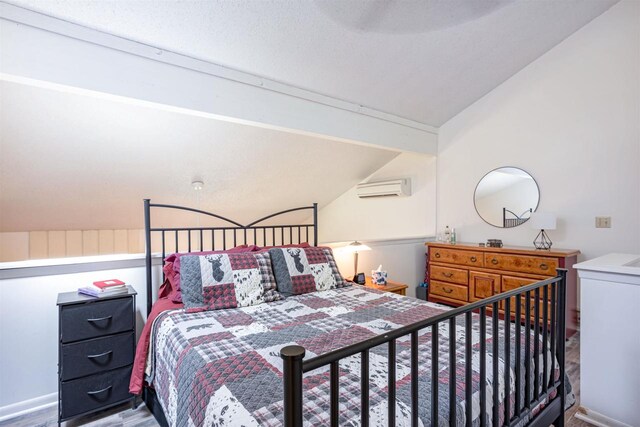 bedroom featuring an AC wall unit and lofted ceiling