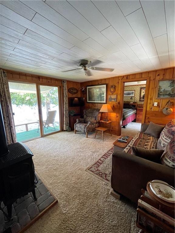 living room featuring wood walls, carpet floors, and a wood stove