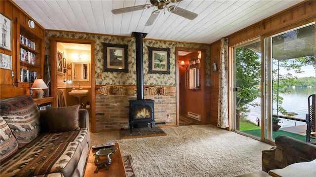 12810 N County Highway T, Hayward, WI 54843 - living area featuring a wood stove, crown molding, a water view, wooden ceiling, and carpet flooring