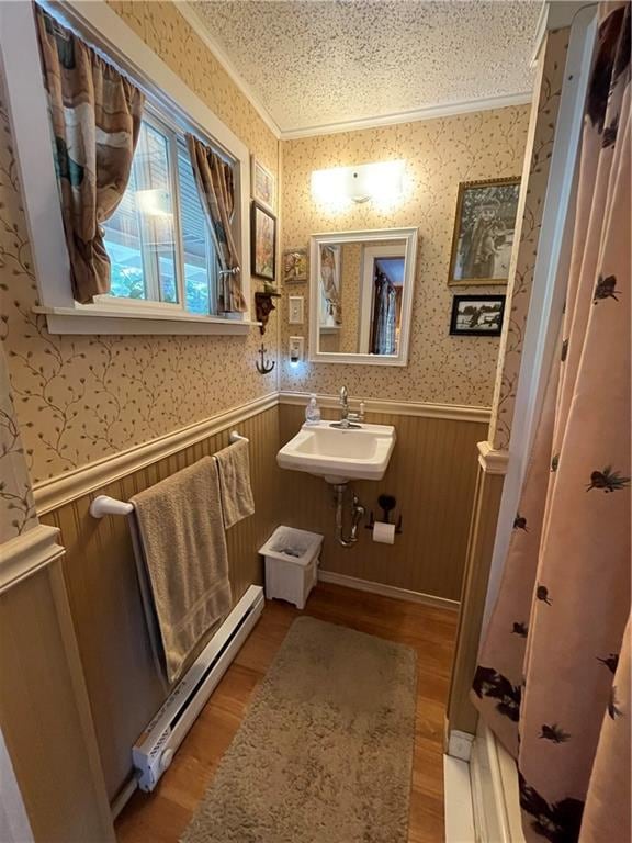 bathroom with a baseboard heating unit, sink, wood-type flooring, and a textured ceiling