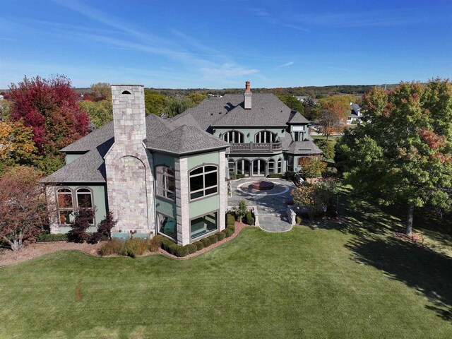 rear view of house with a balcony and a yard