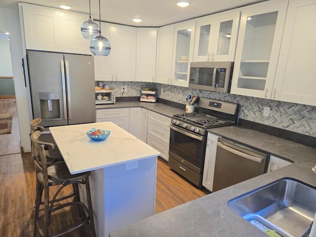 kitchen with stainless steel appliances, white cabinets, dark hardwood / wood-style flooring, and tasteful backsplash