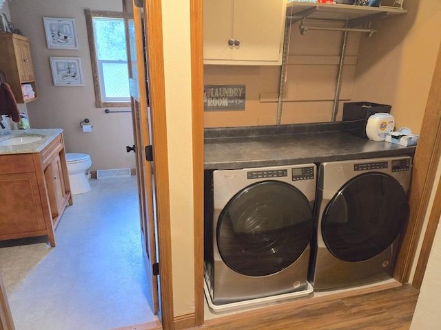 laundry room with sink, washing machine and clothes dryer, and light hardwood / wood-style flooring