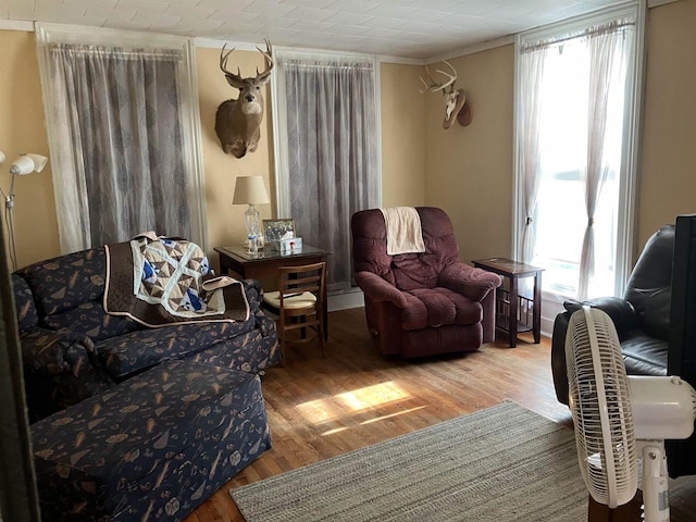 sitting room featuring hardwood / wood-style flooring, ornamental molding, and a healthy amount of sunlight