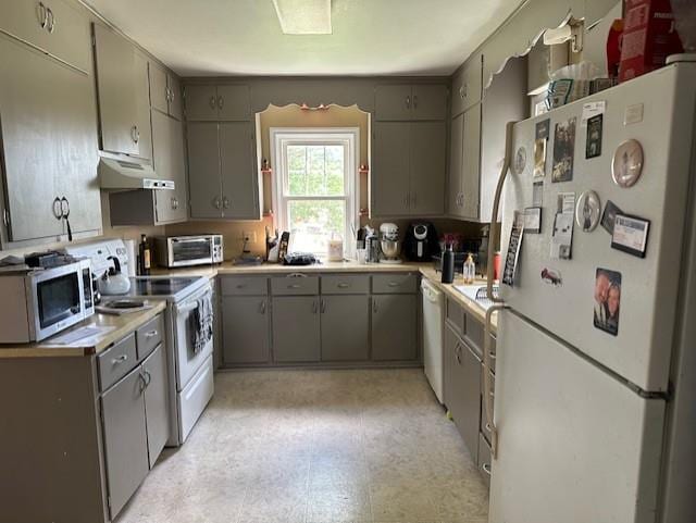 kitchen featuring gray cabinetry, white appliances, and light tile patterned floors