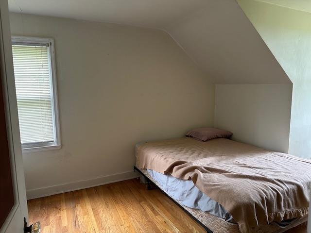 bedroom featuring light wood-type flooring and vaulted ceiling