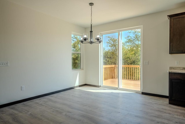 unfurnished dining area with a notable chandelier and light wood-type flooring