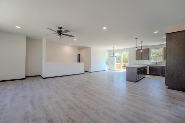 unfurnished living room with sink, light hardwood / wood-style floors, and ceiling fan with notable chandelier