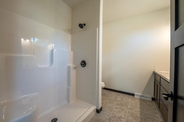 bathroom with a shower, tile patterned flooring, vanity, and toilet