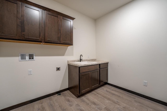 laundry area featuring sink, electric dryer hookup, light hardwood / wood-style flooring, and cabinets