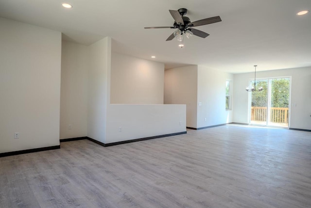 empty room with light hardwood / wood-style flooring and ceiling fan with notable chandelier