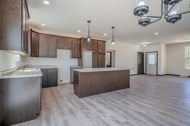 kitchen with light hardwood / wood-style floors, a center island, hanging light fixtures, and sink