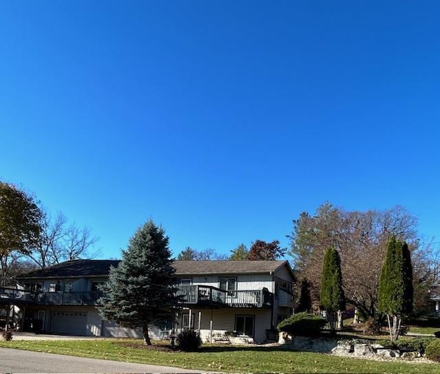 view of front of property featuring a wooden deck, a front yard, and a garage